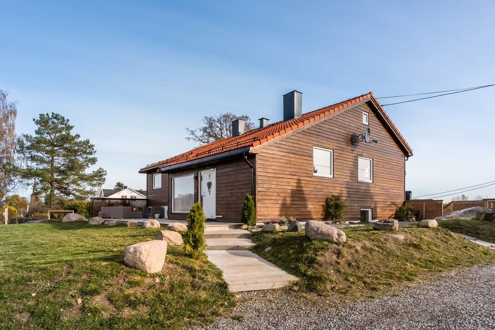 Gavlvegg på eneboligen sett fra hagen, med steinlagt bed langs grunnmuren, Vestby