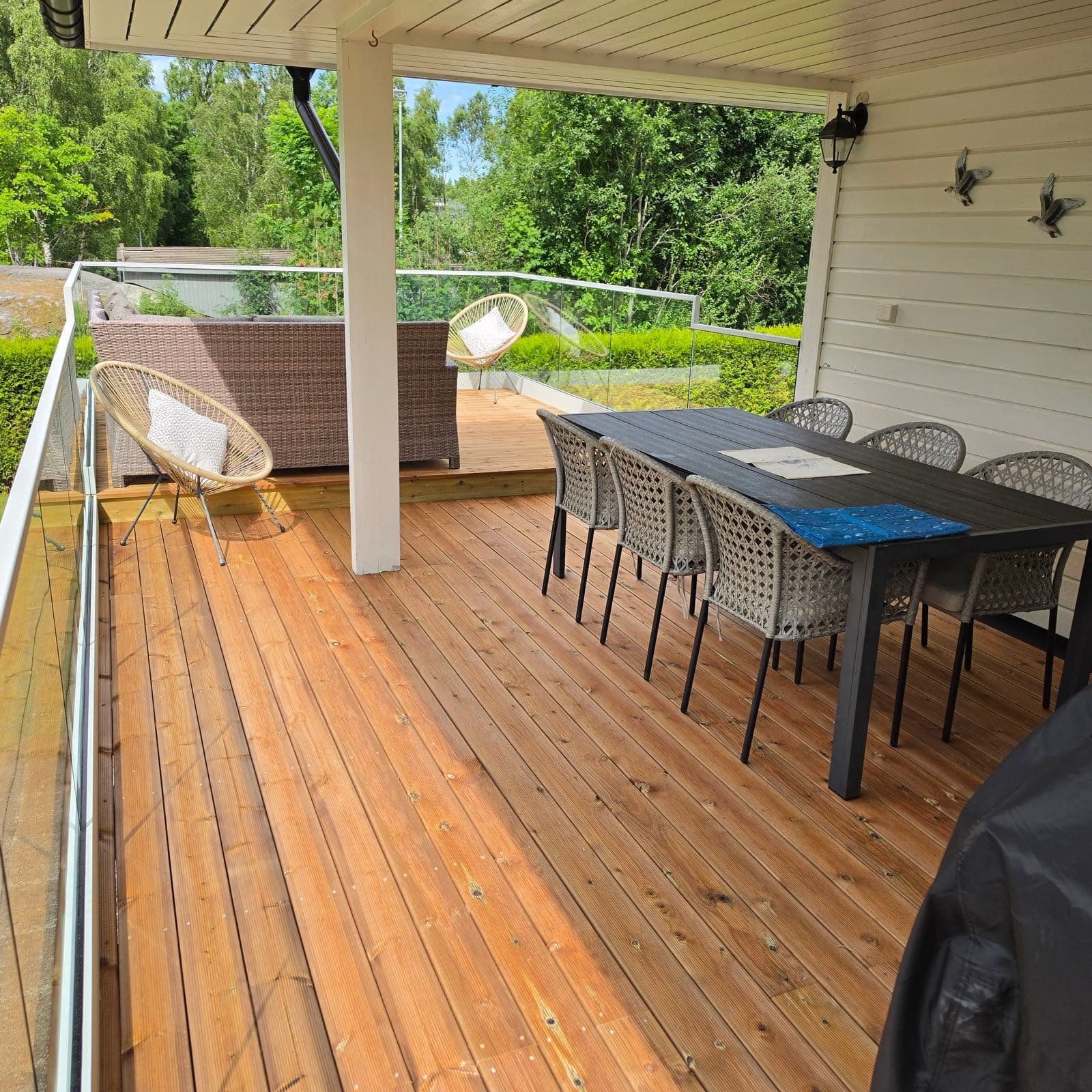 Ferdig møblert terrasse med spisegruppe og loungeplass bak glassrekkverk, Son